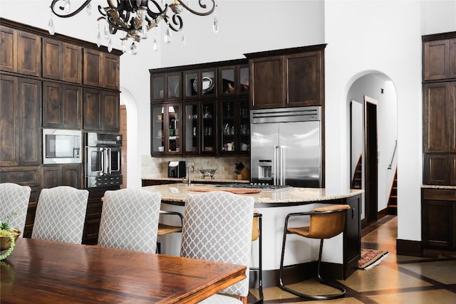 111 Piazza Vetta Dr, Austin, TX 78734 - kitchen with built in appliances, arched walkways, a chandelier, and tasteful backsplash