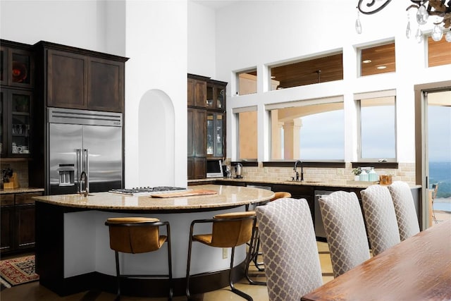 111 Piazza Vetta Dr, Austin, TX 78734 - kitchen featuring built in refrigerator, a sink, a kitchen island, light stone counters, and a high ceiling