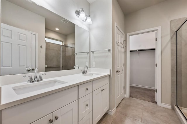 120 Flexus Ln, Liberty Hill, TX 78642 - bathroom with a shower stall, double vanity, a walk in closet, tile patterned flooring, and baseboards
