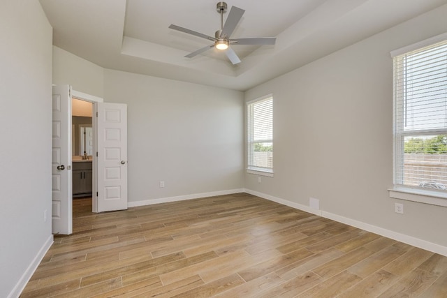110 Denali Dr, Kyle, TX 78640 - unfurnished room featuring a raised ceiling, light wood-style flooring, a ceiling fan, and baseboards