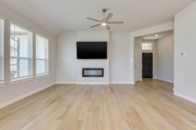 110 Denali Dr, Kyle, TX 78640 - unfurnished living room featuring a glass covered fireplace, ceiling fan, light wood-style flooring, and baseboards