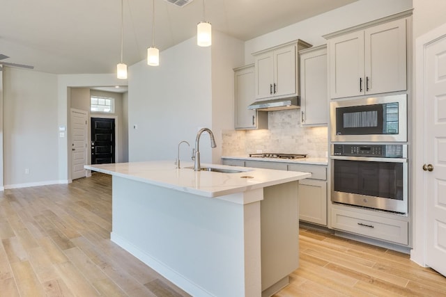 110 Denali Dr, Kyle, TX 78640 - kitchen with a sink, under cabinet range hood, stainless steel gas stovetop, light wood finished floors, and decorative backsplash
