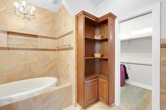 297 Carpers Trl, Fischer, TX 78623 - bathroom featuring a bath, a walk in closet, a chandelier, and wood finished floors
