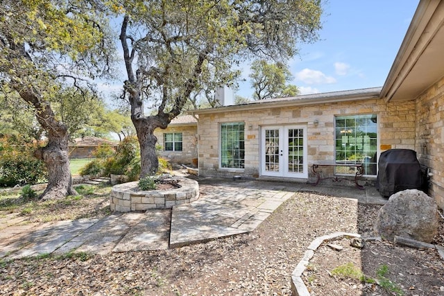 297 Carpers Trl, Fischer, TX 78623 - rear view of house with stone siding, french doors, a patio, and an outdoor fire pit