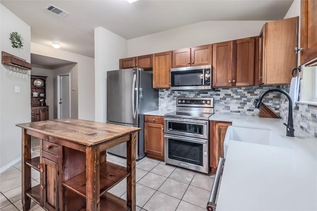 217 Baldwin St, Hutto, TX 78634 - kitchen with stainless steel appliances, light countertops, backsplash, light tile patterned floors, and lofted ceiling