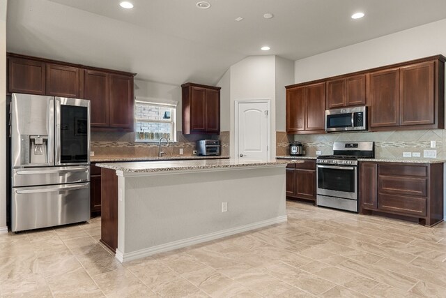 4162 Kingsley Ave, Round Rock, TX 78681 - kitchen featuring stainless steel appliances, lofted ceiling, tasteful backsplash, a center island, and light stone counters