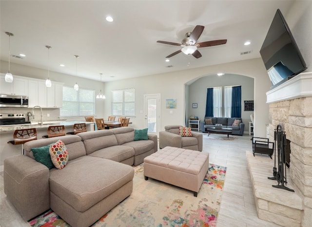 128 Naalehu Ct, Bastrop, TX 78602 - living room with recessed lighting, a stone fireplace, ceiling fan, light wood finished floors, and arched walkways