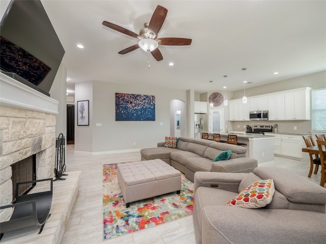 128 Naalehu Ct, Bastrop, TX 78602 - living room featuring a ceiling fan, arched walkways, recessed lighting, a fireplace, and light tile patterned floors