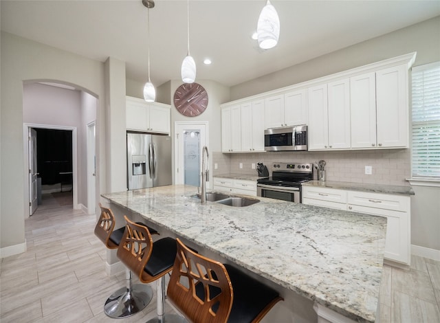 128 Naalehu Ct, Bastrop, TX 78602 - kitchen featuring stainless steel appliances, a sink, arched walkways, baseboards, and tasteful backsplash