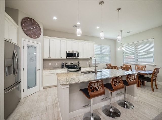 128 Naalehu Ct, Bastrop, TX 78602 - kitchen featuring stainless steel appliances, a sink, a kitchen bar, backsplash, and light stone counters