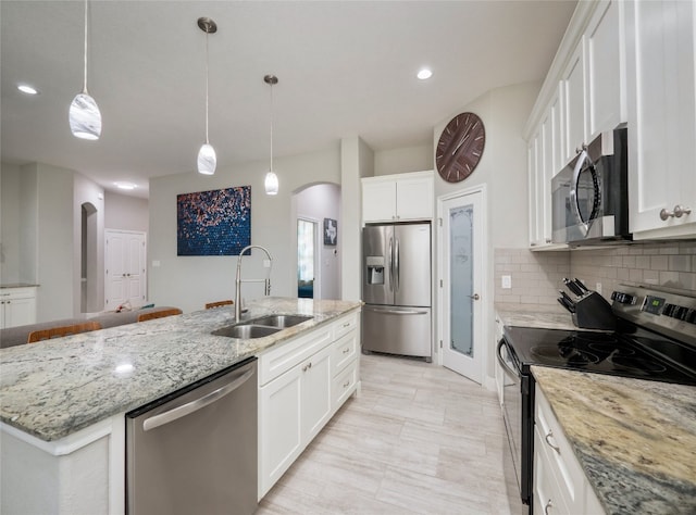 128 Naalehu Ct, Bastrop, TX 78602 - kitchen featuring stainless steel appliances, a sink, arched walkways, an island with sink, and decorative backsplash