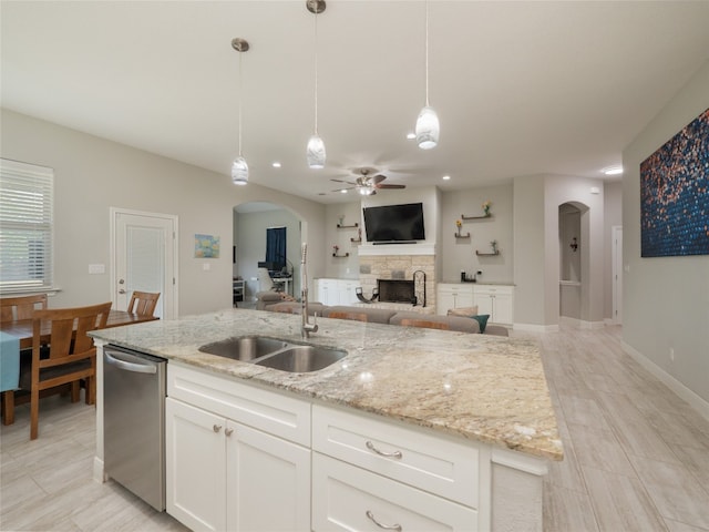 128 Naalehu Ct, Bastrop, TX 78602 - kitchen with dishwasher, a fireplace, a sink, arched walkways, and a ceiling fan