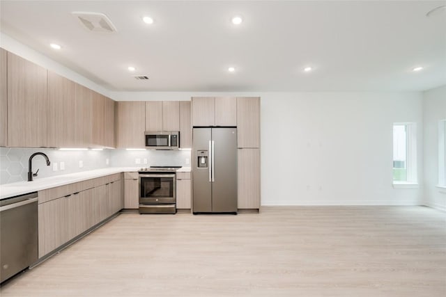 4802 S Congress Ave Unit 121, Austin, TX 78745 - kitchen with stainless steel appliances, light brown cabinets, decorative backsplash, light countertops, and recessed lighting