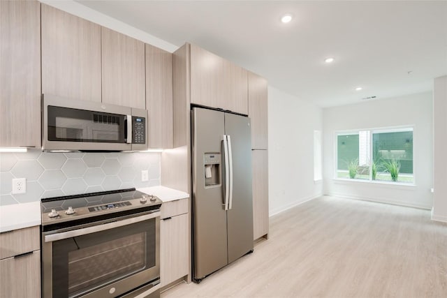 4802 S Congress Ave Unit 121, Austin, TX 78745 - kitchen featuring appliances with stainless steel finishes, light countertops, modern cabinets, tasteful backsplash, and light wood-type flooring