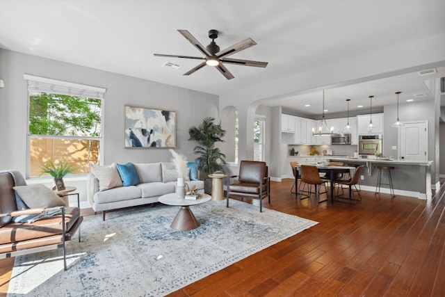 7820 Oteka Cv, Austin, TX 78735 - living room featuring dark wood-style floors, baseboards, ceiling fan, and arched walkways