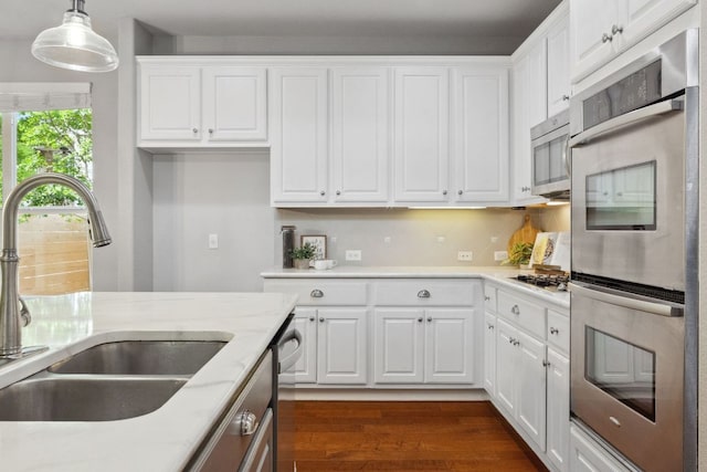 7820 Oteka Cv, Austin, TX 78735 - kitchen featuring appliances with stainless steel finishes, white cabinets, decorative light fixtures, and dark wood-type flooring