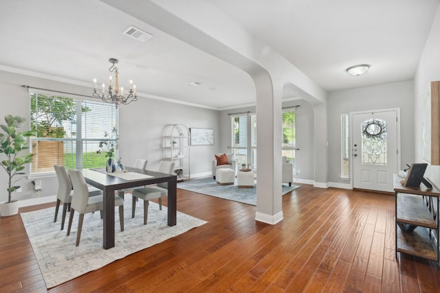 7820 Oteka Cv, Austin, TX 78735 - dining space featuring a chandelier, arched walkways, dark wood finished floors, baseboards, and healthy amount of natural light