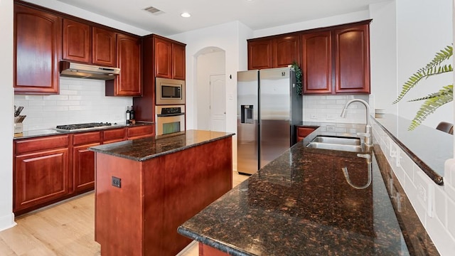 30 Stone Terrace Dr, Austin, TX 78734 - kitchen with stainless steel appliances, a sink, under cabinet range hood, reddish brown cabinets, and a kitchen island