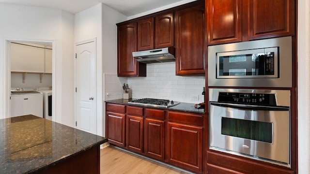 30 Stone Terrace Dr, Austin, TX 78734 - kitchen with stainless steel appliances, separate washer and dryer, dark stone counters, under cabinet range hood, and tasteful backsplash