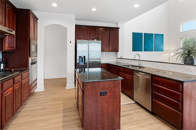 30 Stone Terrace Dr, Austin, TX 78734 - kitchen with appliances with stainless steel finishes, a peninsula, a center island, arched walkways, and light wood-type flooring