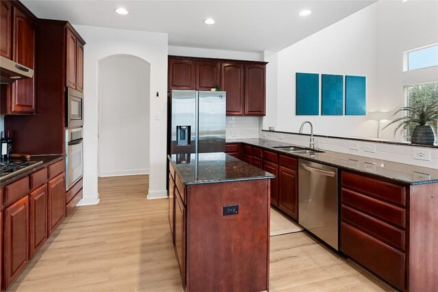 30 Stone Terrace Dr, Austin, TX 78734 - kitchen with appliances with stainless steel finishes, a peninsula, a kitchen island, arched walkways, and light wood-style floors