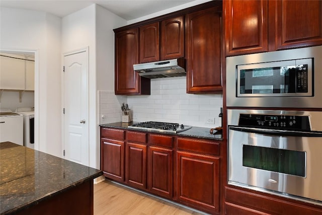 30 Stone Terrace Dr, Austin, TX 78734 - kitchen with stainless steel appliances, washer and clothes dryer, dark stone countertops, under cabinet range hood, and tasteful backsplash