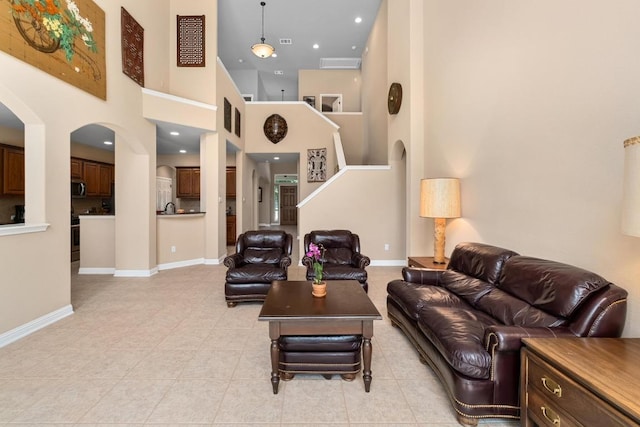 161 Serene Hollow Ln, Buda, TX 78610 - living area with light tile patterned floors, baseboards, arched walkways, and a high ceiling