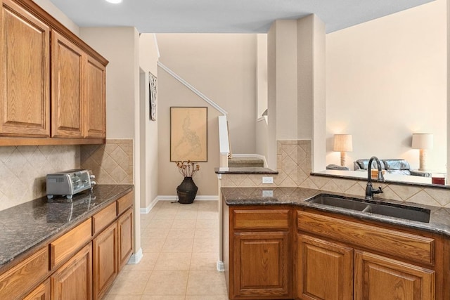 161 Serene Hollow Ln, Buda, TX 78610 - kitchen with a sink, brown cabinetry, decorative backsplash, and dark stone countertops