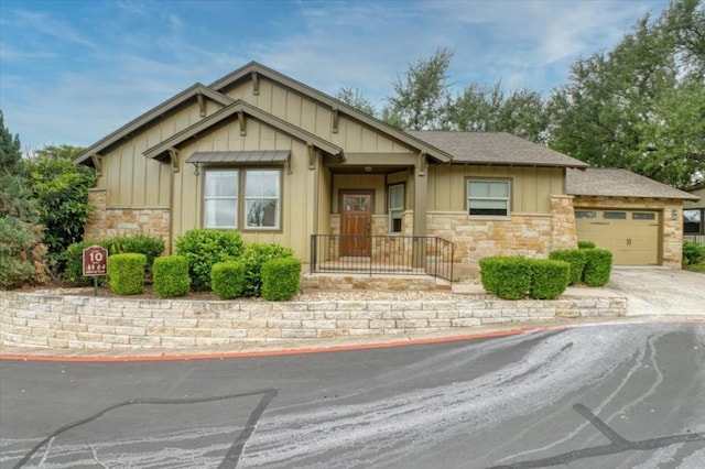14501 Falcon Head Blvd Unit 43, Austin, TX 78738 - view of front of house featuring board and batten siding, stone siding, a garage, driveway, and roof with shingles