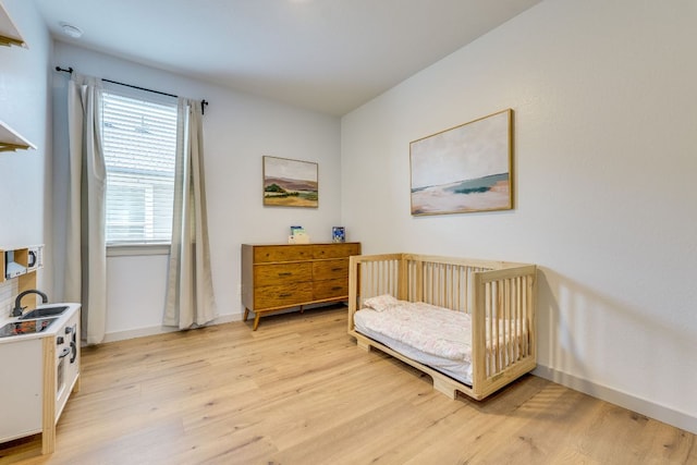 98 Barton Creek Ln, Hutto, TX 78634 - bedroom featuring light wood-style flooring, baseboards, a crib, and a sink