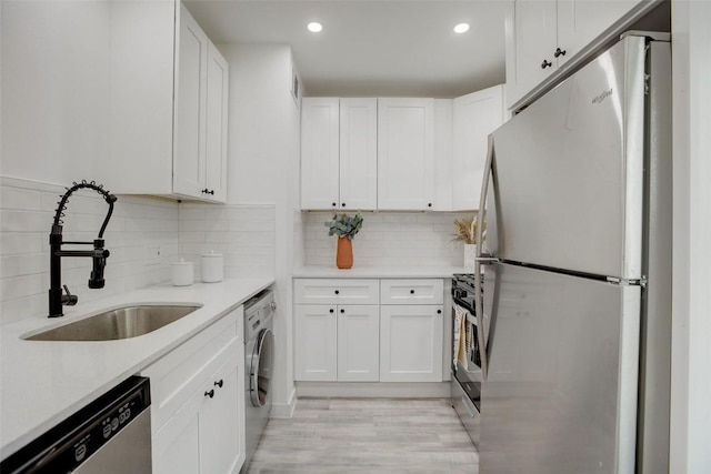 1200 E 52nd St Unit 105, Austin, TX 78723 - kitchen featuring appliances with stainless steel finishes, a sink, washer / dryer, recessed lighting, and white cabinets
