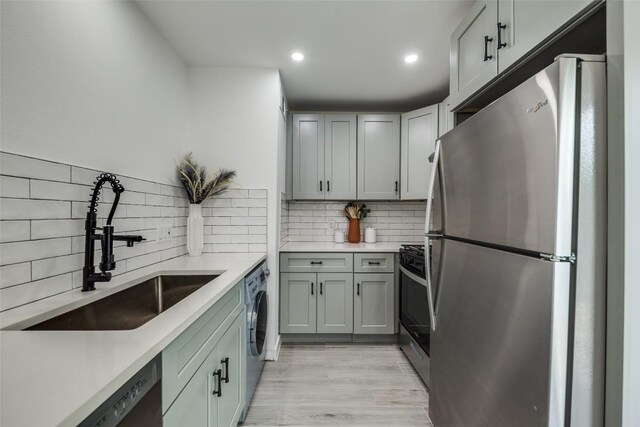 1200 E 52nd St Unit 105, Austin, TX 78723 - kitchen with appliances with stainless steel finishes, a sink, washer / clothes dryer, decorative backsplash, and light countertops