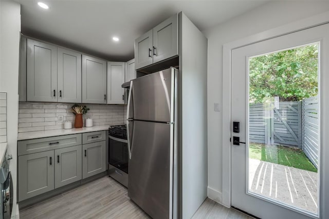 1200 E 52nd St Unit 105, Austin, TX 78723 - kitchen with stainless steel appliances, gray cabinets, decorative backsplash, light countertops, and light wood-type flooring