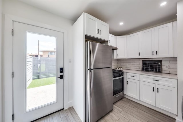 1200 E 52nd St Unit 105, Austin, TX 78723 - kitchen with appliances with stainless steel finishes, light countertops, white cabinetry, tasteful backsplash, and under cabinet range hood