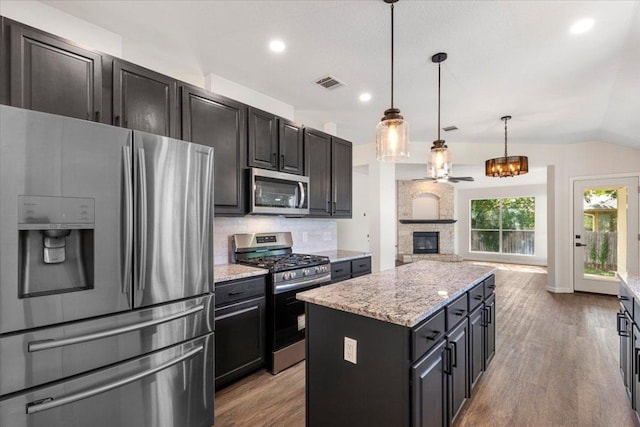 404 N Belinda Ct, Bastrop, TX 78602 - kitchen with stainless steel appliances, wood finished floors, open floor plan, a center island, and light stone countertops