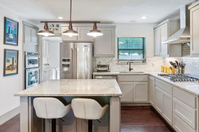 5701 Ave G, Austin, TX 78752 - kitchen with stainless steel appliances, wall chimney range hood, separate washer and dryer, tasteful backsplash, and light stone counters