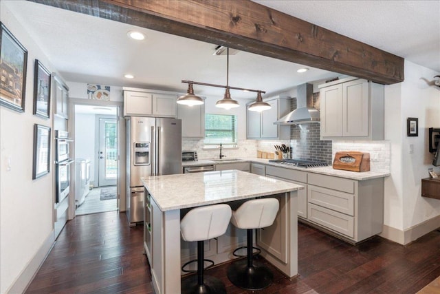 5701 Ave G, Austin, TX 78752 - kitchen featuring wall chimney range hood, stainless steel appliances, tasteful backsplash, dark wood-style floors, and recessed lighting