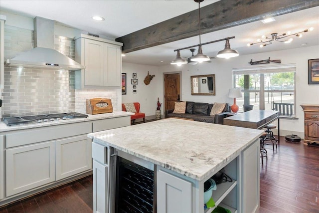 5701 Ave G, Austin, TX 78752 - kitchen featuring wall chimney exhaust hood, stainless steel gas stovetop, beverage cooler, backsplash, and dark wood-style flooring