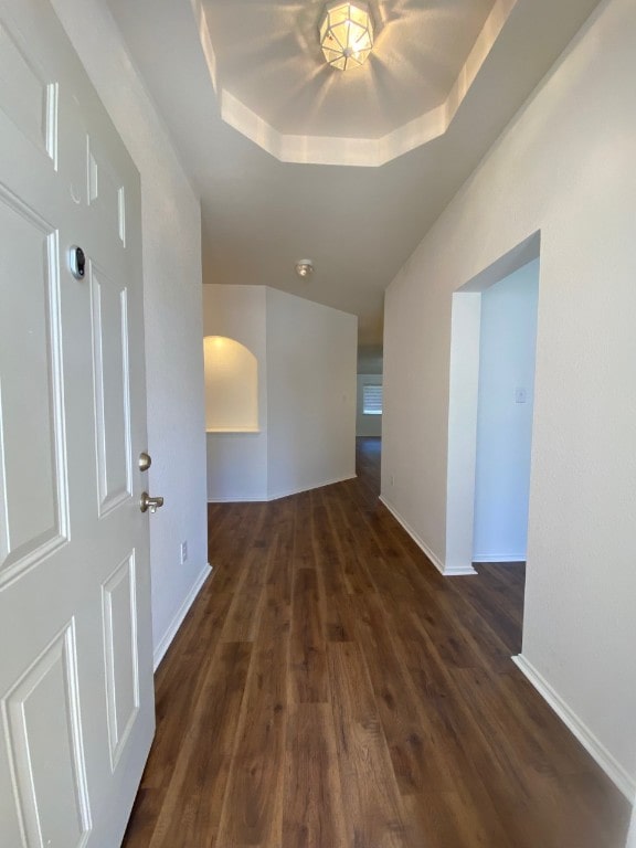 1119 Burgess Dr, Leander, TX 78641 - hallway featuring dark wood-style floors, arched walkways, and a raised ceiling