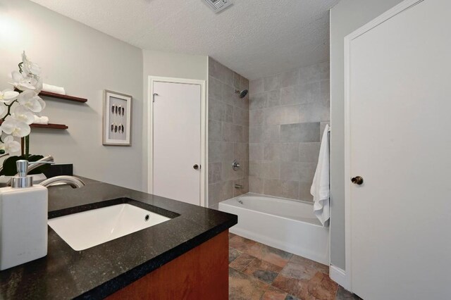 2405 Monarch Dr, Austin, TX 78748 - full bath with bathing tub / shower combination, vanity, stone finish floors, a textured ceiling, and baseboards
