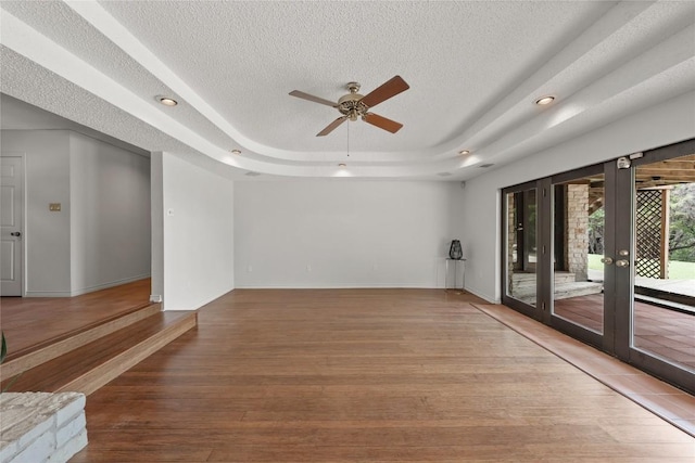 11105 Highview Dr, Belton, TX 76513 - spare room featuring french doors, a textured ceiling, a tray ceiling, light wood-type flooring, and a ceiling fan