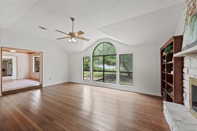 11105 Highview Dr, Belton, TX 76513 - unfurnished living room featuring a stone fireplace, wood finished floors, lofted ceiling, ceiling fan, and a textured ceiling