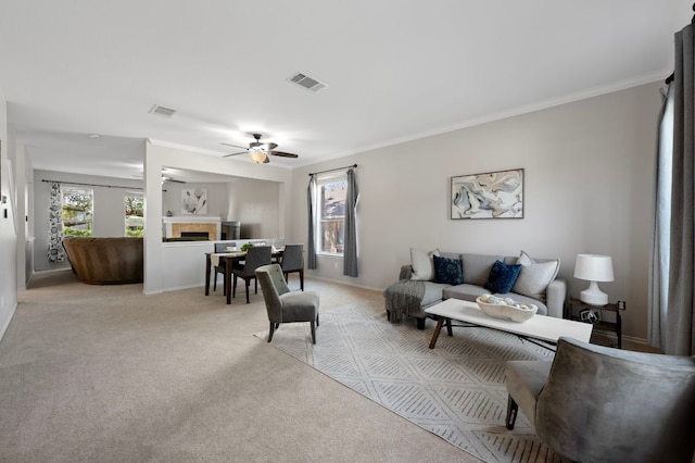 145 Trinity Dr, Kyle, TX 78640 - living area featuring light carpet, a fireplace, ceiling fan, baseboards, and ornamental molding