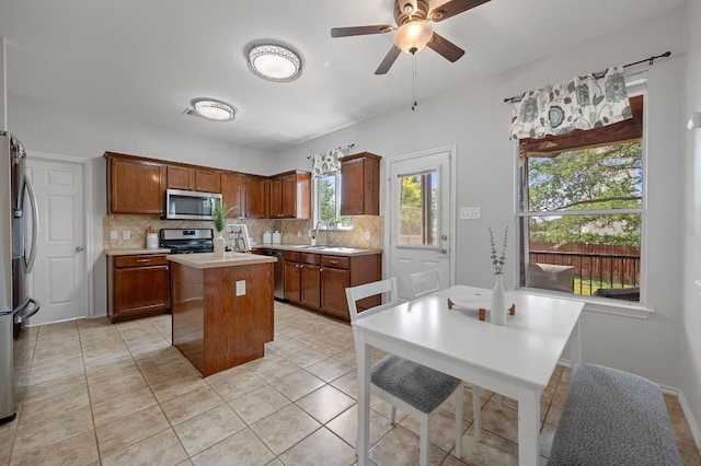 145 Trinity Dr, Kyle, TX 78640 - kitchen with appliances with stainless steel finishes, a kitchen island, decorative backsplash, light countertops, and ceiling fan