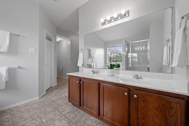 145 Trinity Dr, Kyle, TX 78640 - bathroom with double vanity, a stall shower, tile patterned flooring, baseboards, and lofted ceiling