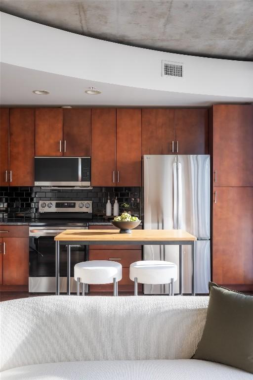 360 Nueces St Unit 1503, Austin, TX 78701 - kitchen featuring stainless steel appliances, tasteful backsplash, and dark countertops