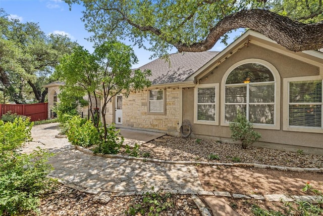16 Troon Dr, Lakeway, TX 78738 - view of property exterior with stucco siding, stone siding, roof with shingles, and a patio