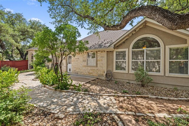 16 Troon Dr, Lakeway, TX 78738 - view of property exterior featuring stucco siding, stone siding, roof with shingles, and a patio area