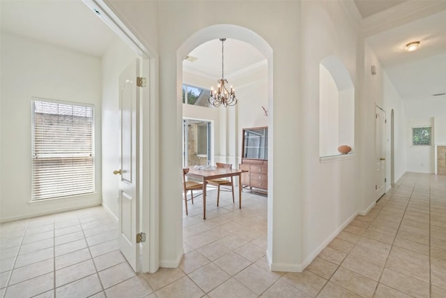 16 Troon Dr, Lakeway, TX 78738 - hall featuring light tile patterned floors, arched walkways, a chandelier, a towering ceiling, and baseboards