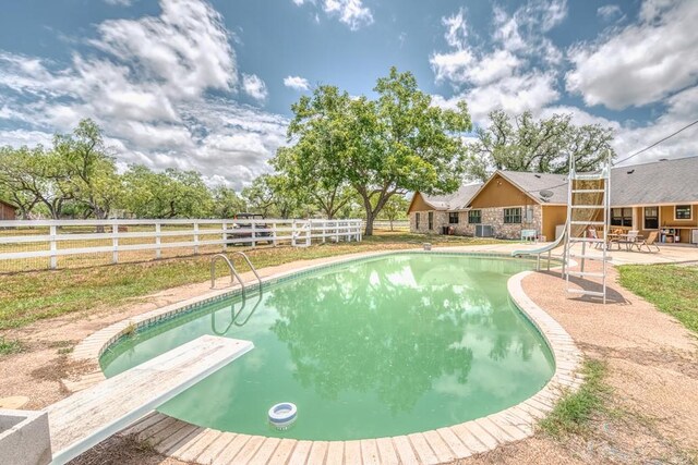 701 W Steele St, Smiley, TX 78159 - view of swimming pool featuring a diving board, a water slide, a patio area, and a fenced backyard